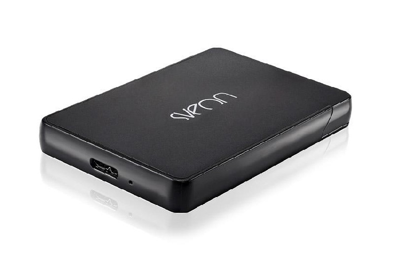 Un disco duro externo negro y rectangular con la marca 'Synology' sobre una superficie blanca. Tiene un puerto USB.
