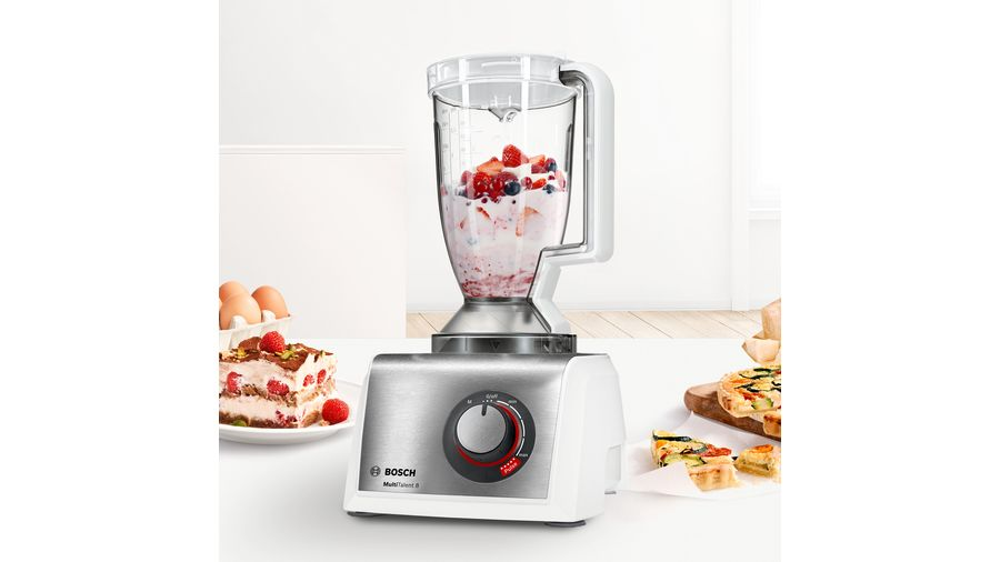 Mixeur avec fruits, nourriture sur table. Oeufs et pâtisserie à côté.