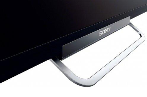 Soporte de TV Sony negro con asa plateada sobre superficie blanca.