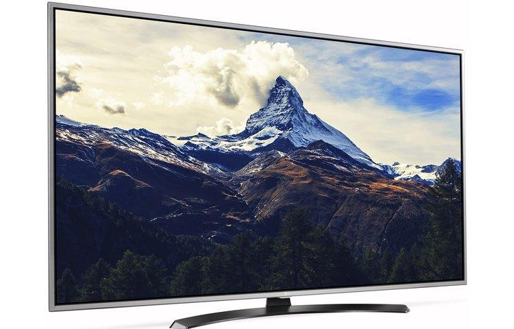 Un televisor de pantalla ancha muestra una escena de montaña, enmarcada en negro con detalles plateados.