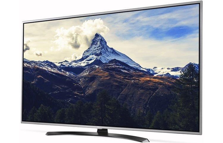 El televisor muestra una escena de montaña. Nubes blancas rodean el pico. Colinas marrones y árboles verdes en primer plano.