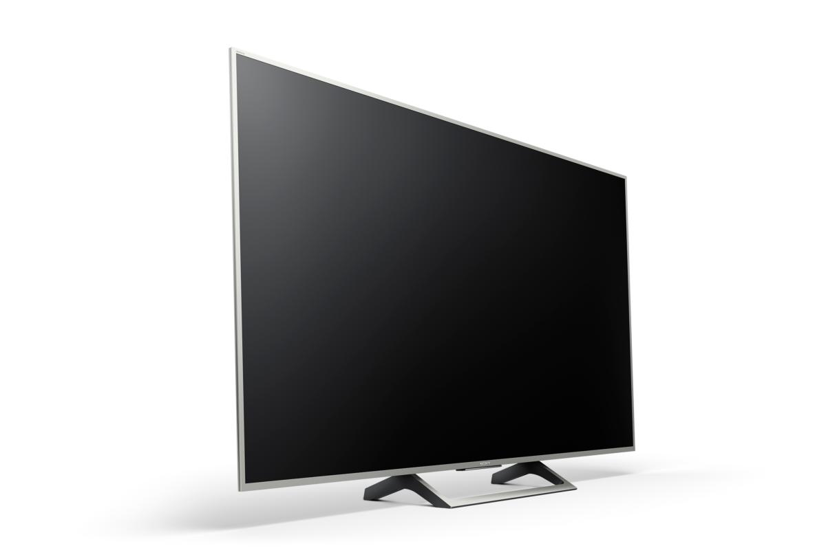 Televisor moderno, con un marco plateado delgado y una pantalla negra, en una superficie blanca.