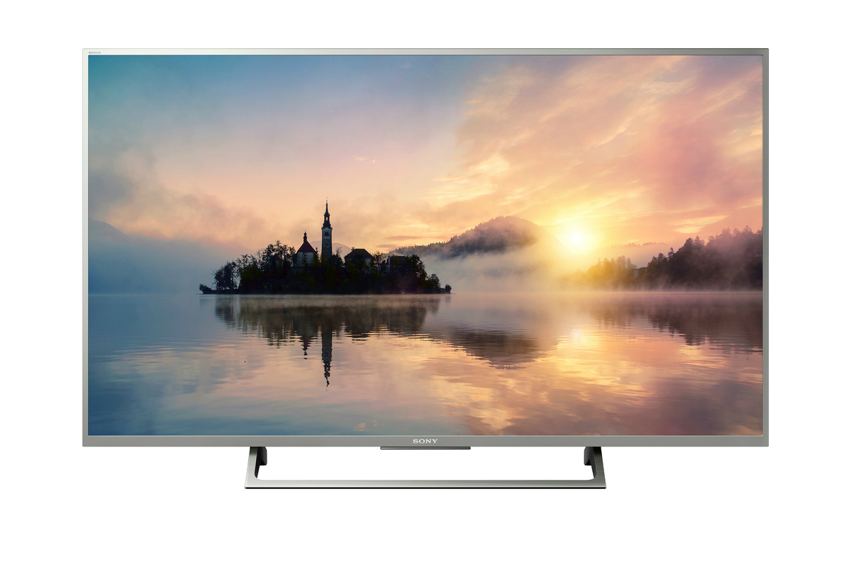 Un televisor Sony mostrando un lago con una iglesia, puesta de sol y niebla.