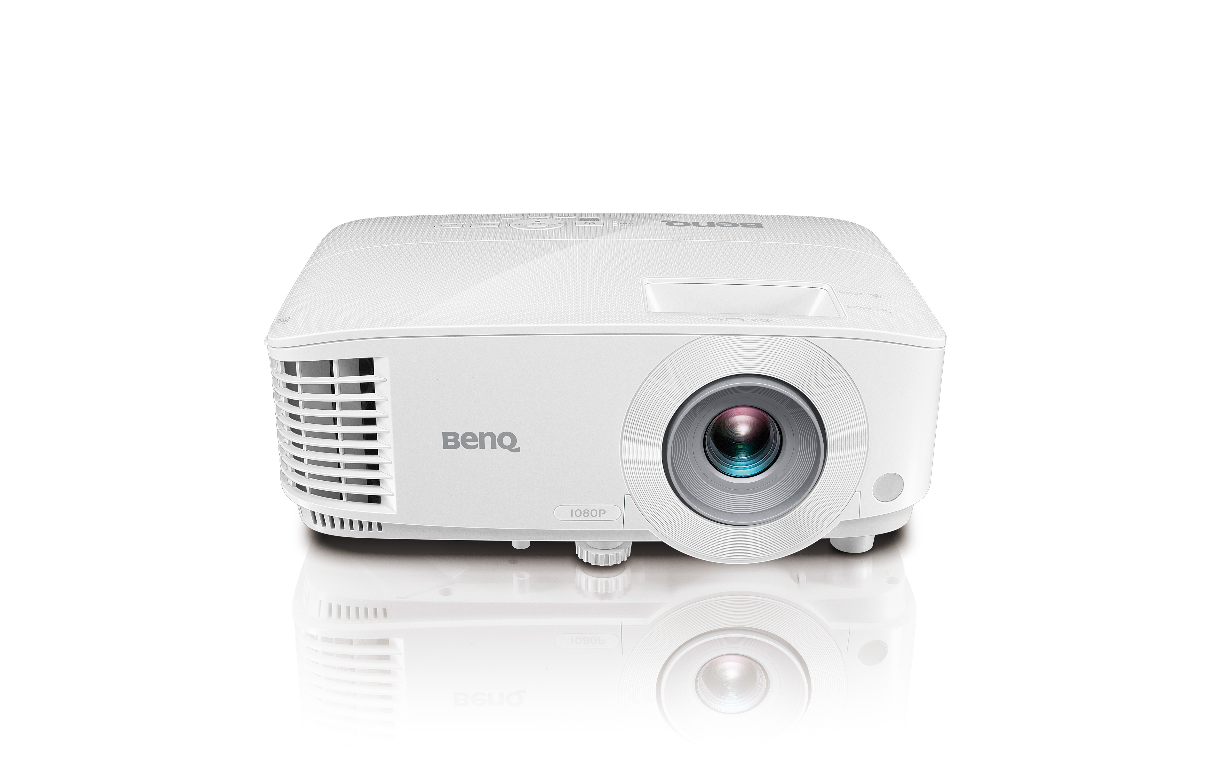 Un proyector BenQ blanco sobre una superficie blanca, con lente y ventilas visibles. Una reflexión debajo.