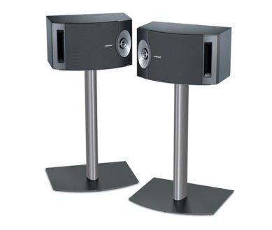 Dos altavoces Bose negros sobre soportes plateados con bases negras, sobre fondo blanco.