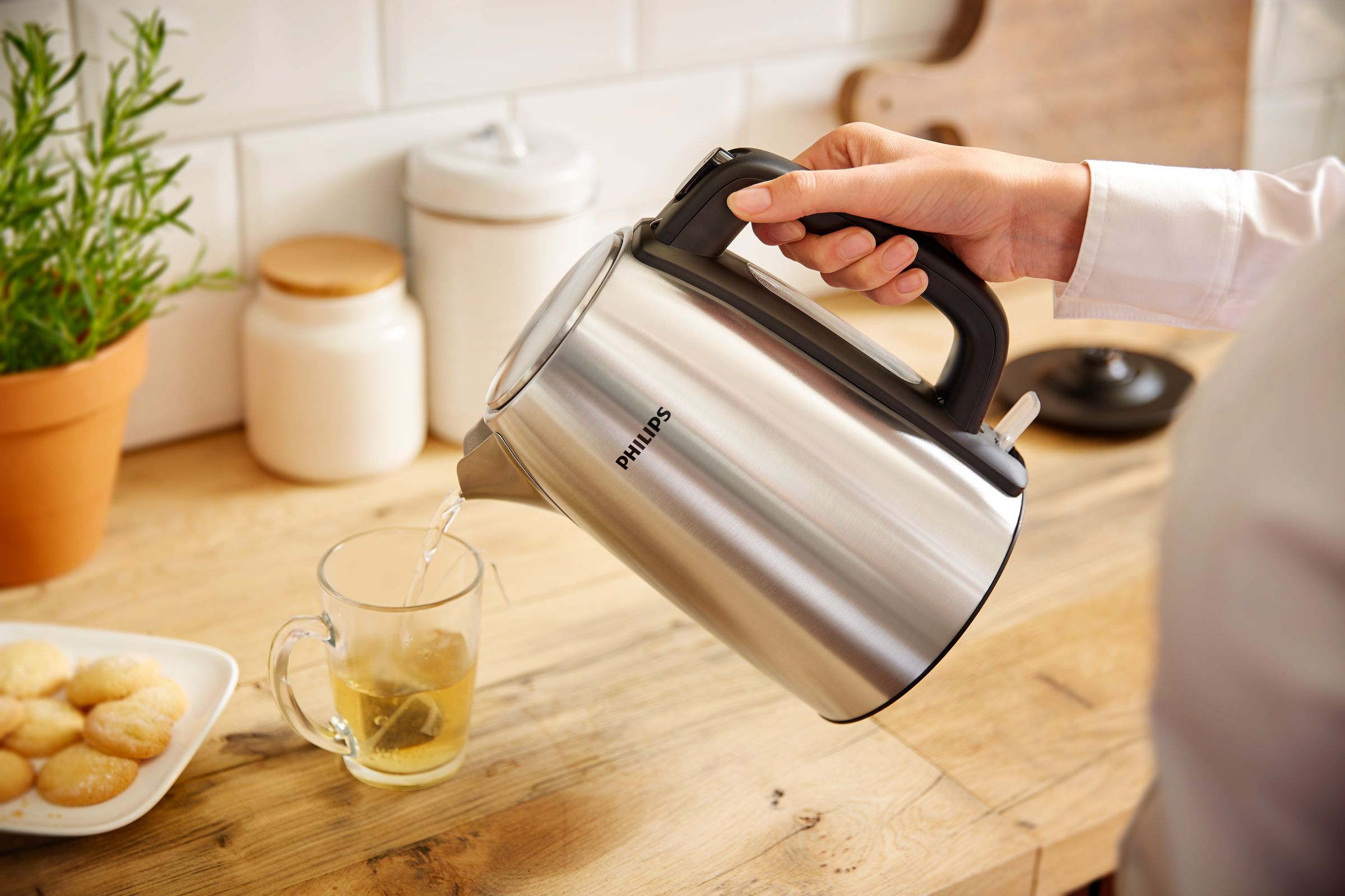 Eine Person gießt Wasser aus einem Philips-Wasserkocher in ein Glas.