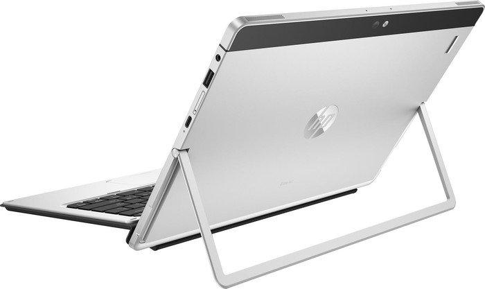 Tableta HP plateada sobre un soporte. La pantalla mira hacia arriba, mostrando una pantalla. Teclado negro en la parte inferior.