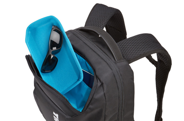 Mochila negra con gafas de sol en estuche azul. Parcialmente abierta, mostrando el contenido.