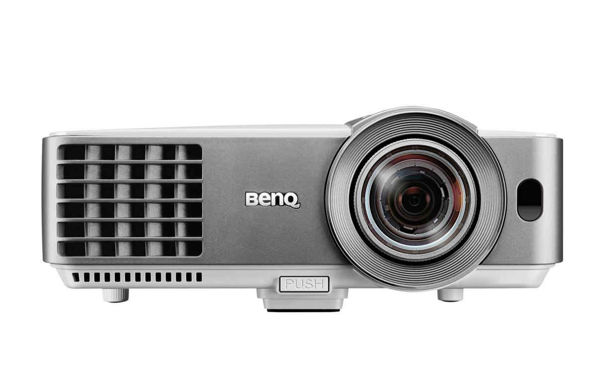 Proyector BenQ plateado y blanco, vista frontal sobre fondo blanco. Botón visible.