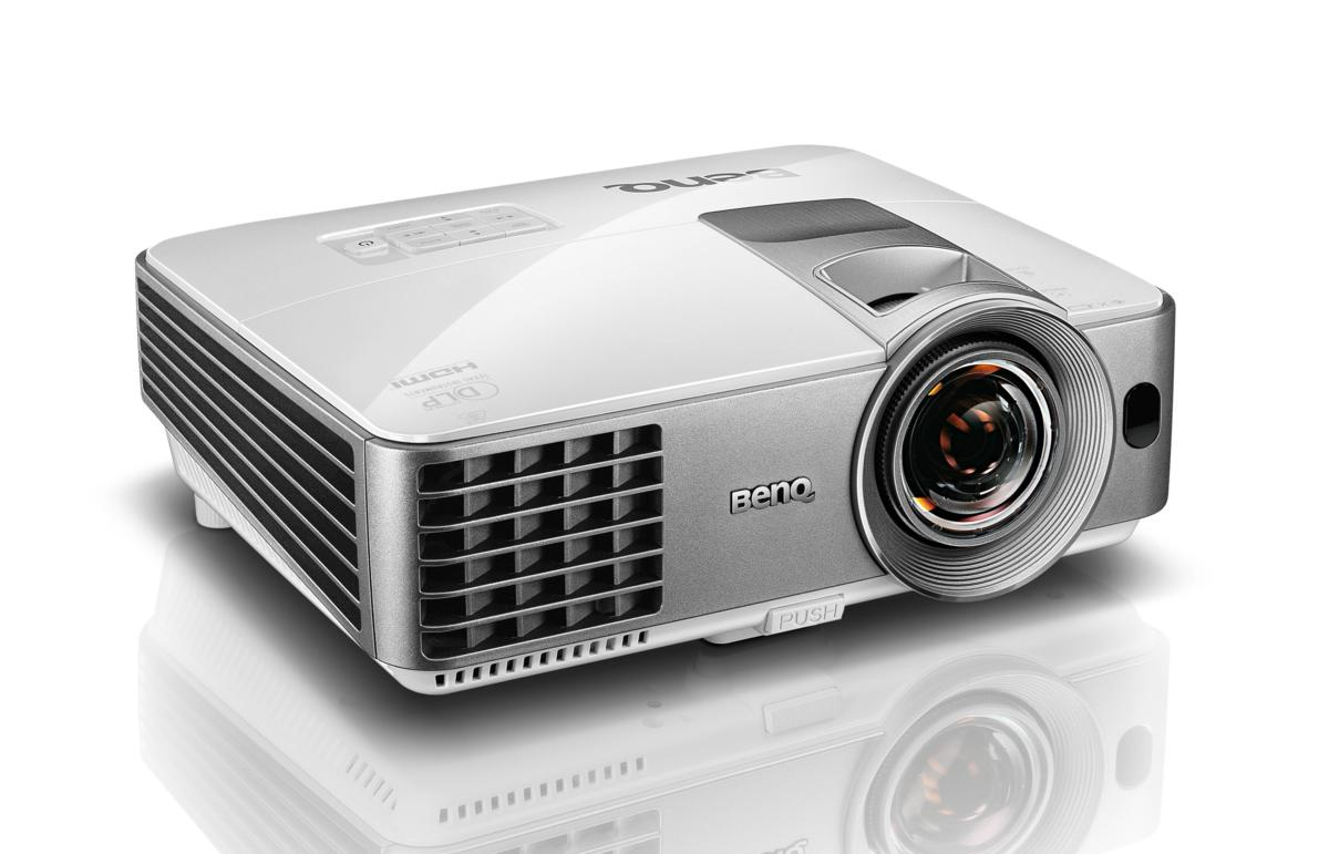 Proyector BenQ blanco y plateado. El proyector está sobre una superficie blanca.
