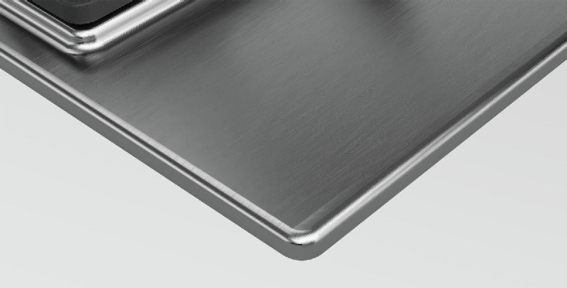Primer plano de superficie metálica cepillada con borde brillante y reflectante.