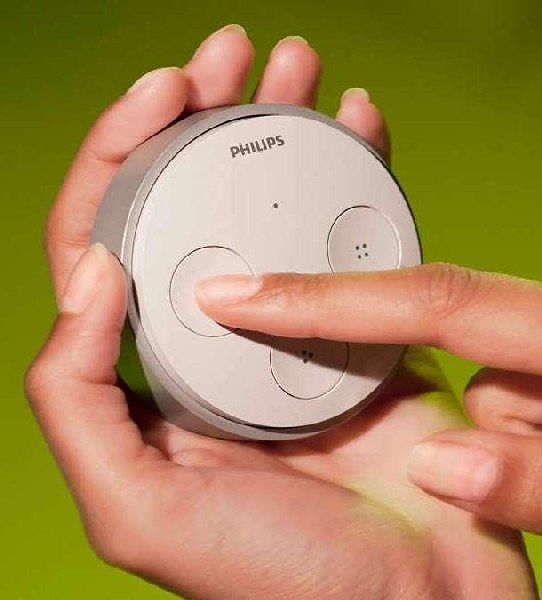Mano sosteniendo un dispositivo Philips gris, dedo presionando un botón.