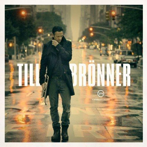 Till Brönner Albumcover. Der Künstler steht auf einer Stadtstraße und hält eine Trompete, Regen auf der Straße.