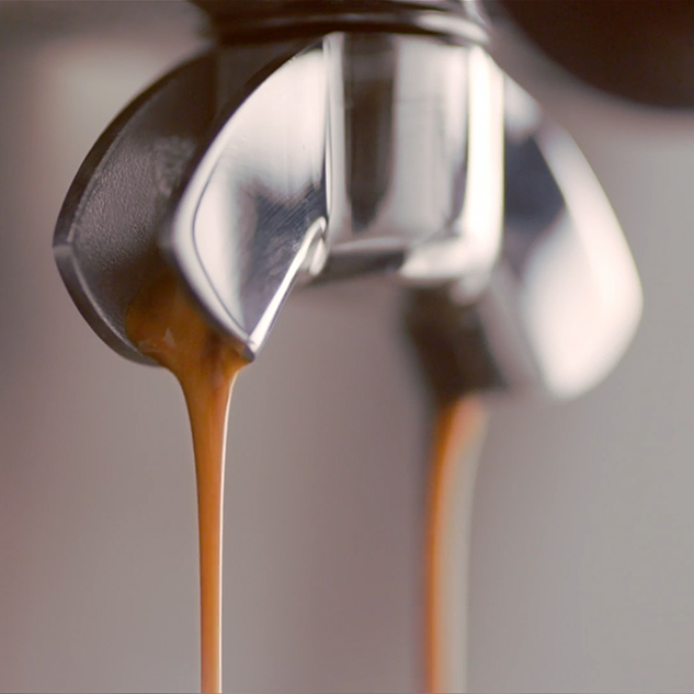 Espresso folyik ki egy gépből. A kávé sötétbarna és lefelé folyik.
