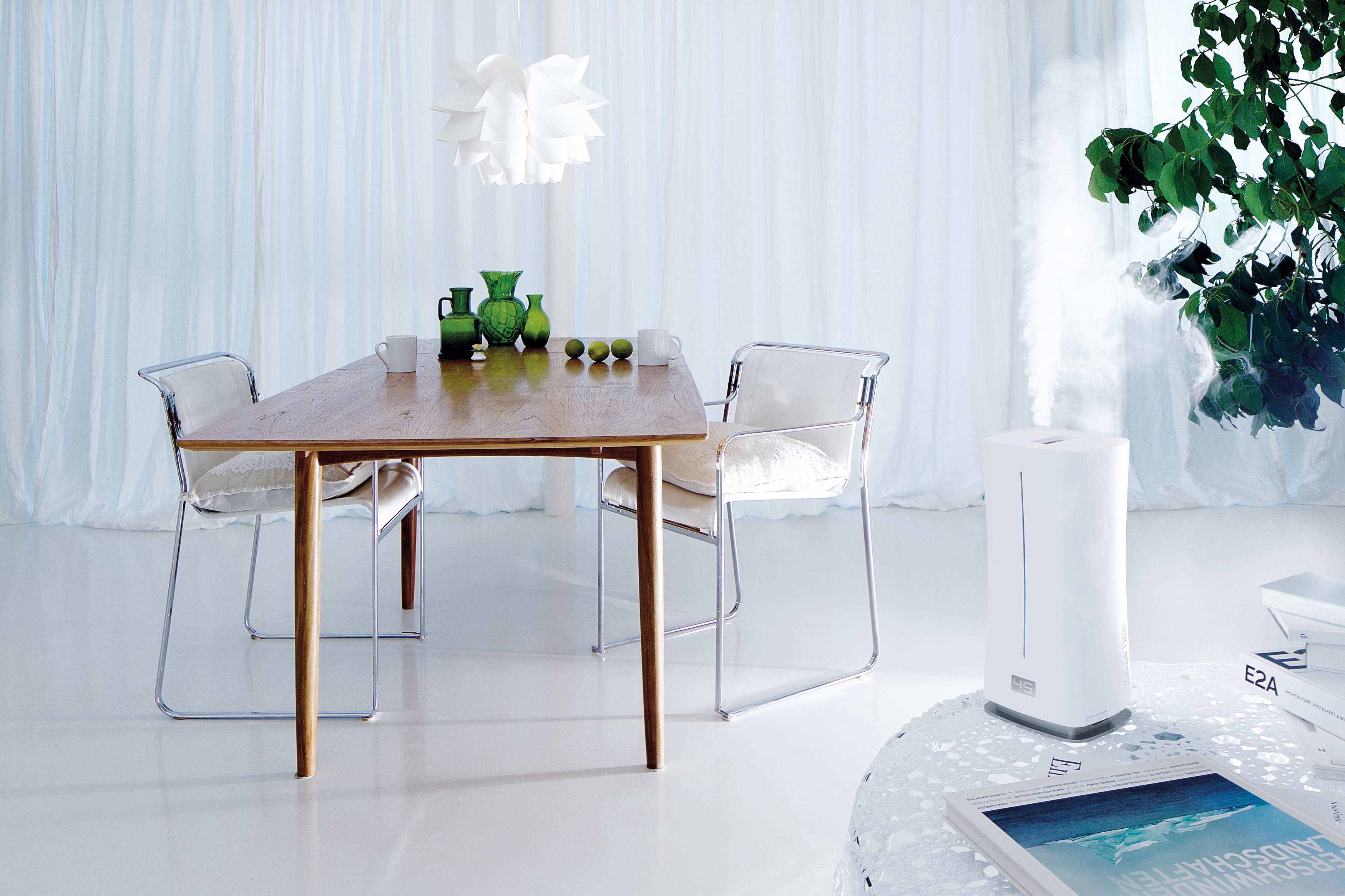 Esszimmer mit Holztisch, Stühlen und weißem Luftbefeuchter. Hintergrund: weiße Wände.