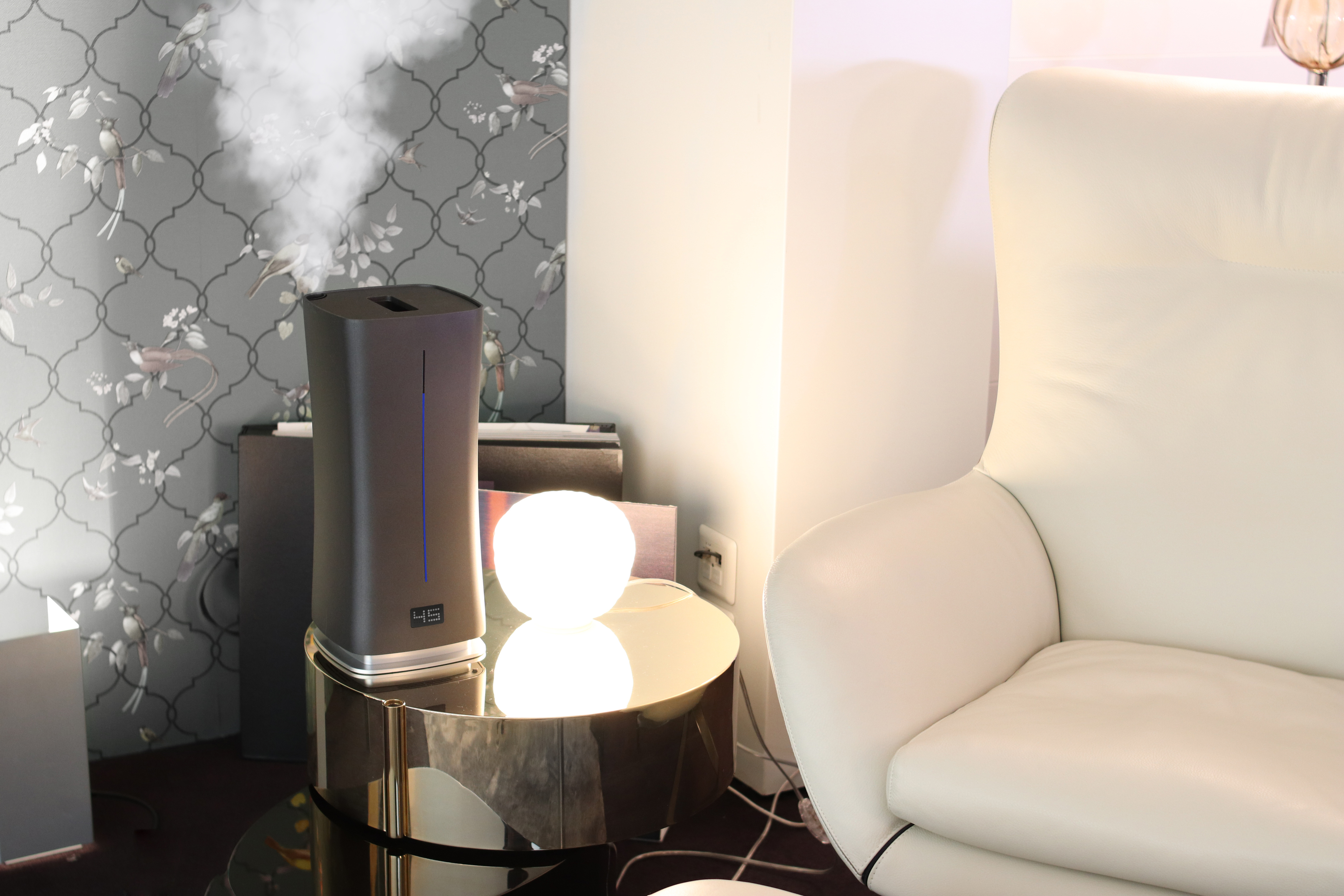 Luftbefeuchter auf dem Tisch. Rauch tritt aus. Lampe und weißes Sofa im Hintergrund.