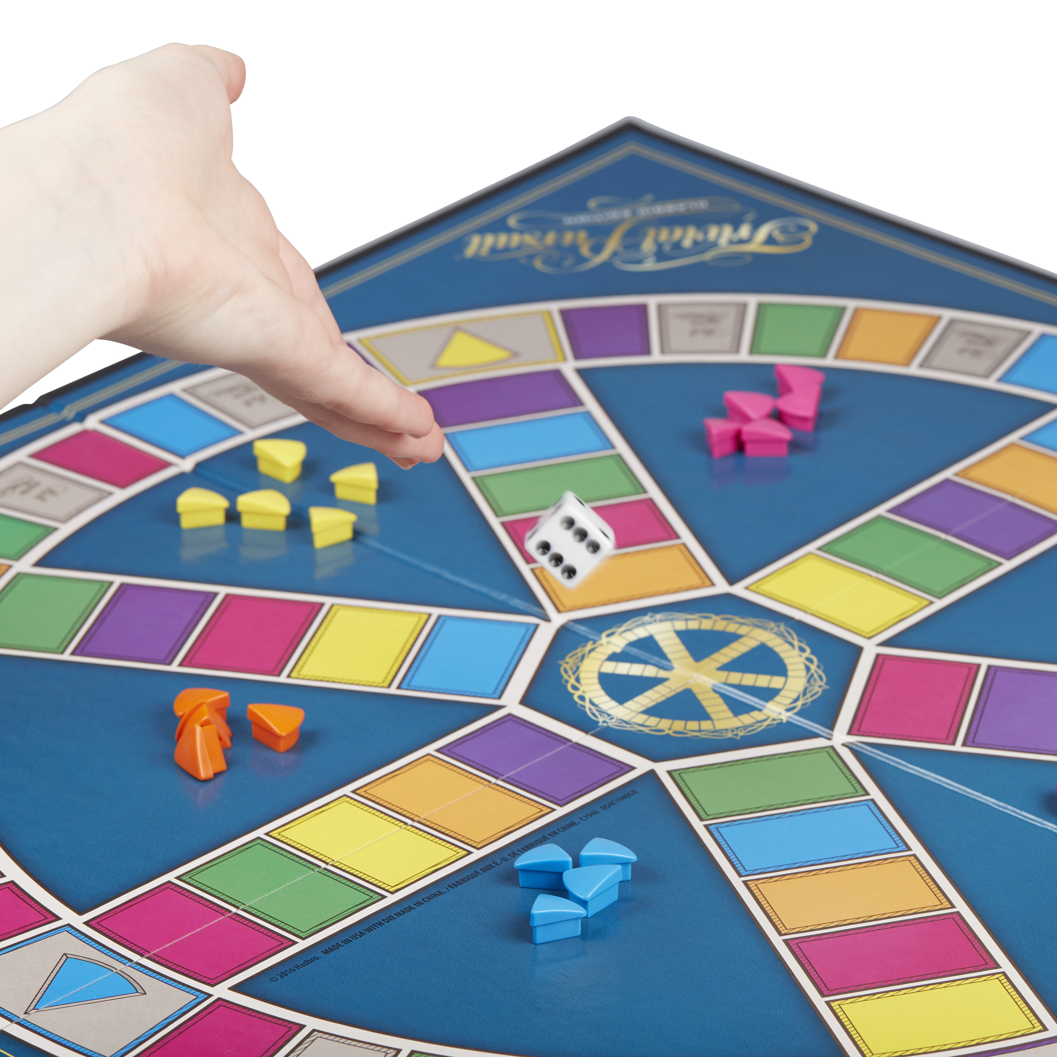Eine Hand wirft einen Würfel auf ein Trivial Pursuit-Brett. Bunte Keile und Spielsteine ​​sind auf dem Brett verstreut.