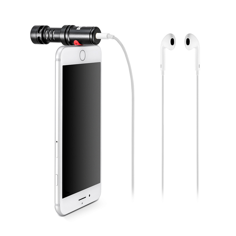 Micro noir fixé à un téléphone argenté. Écouteurs blancs connectés, isolé.