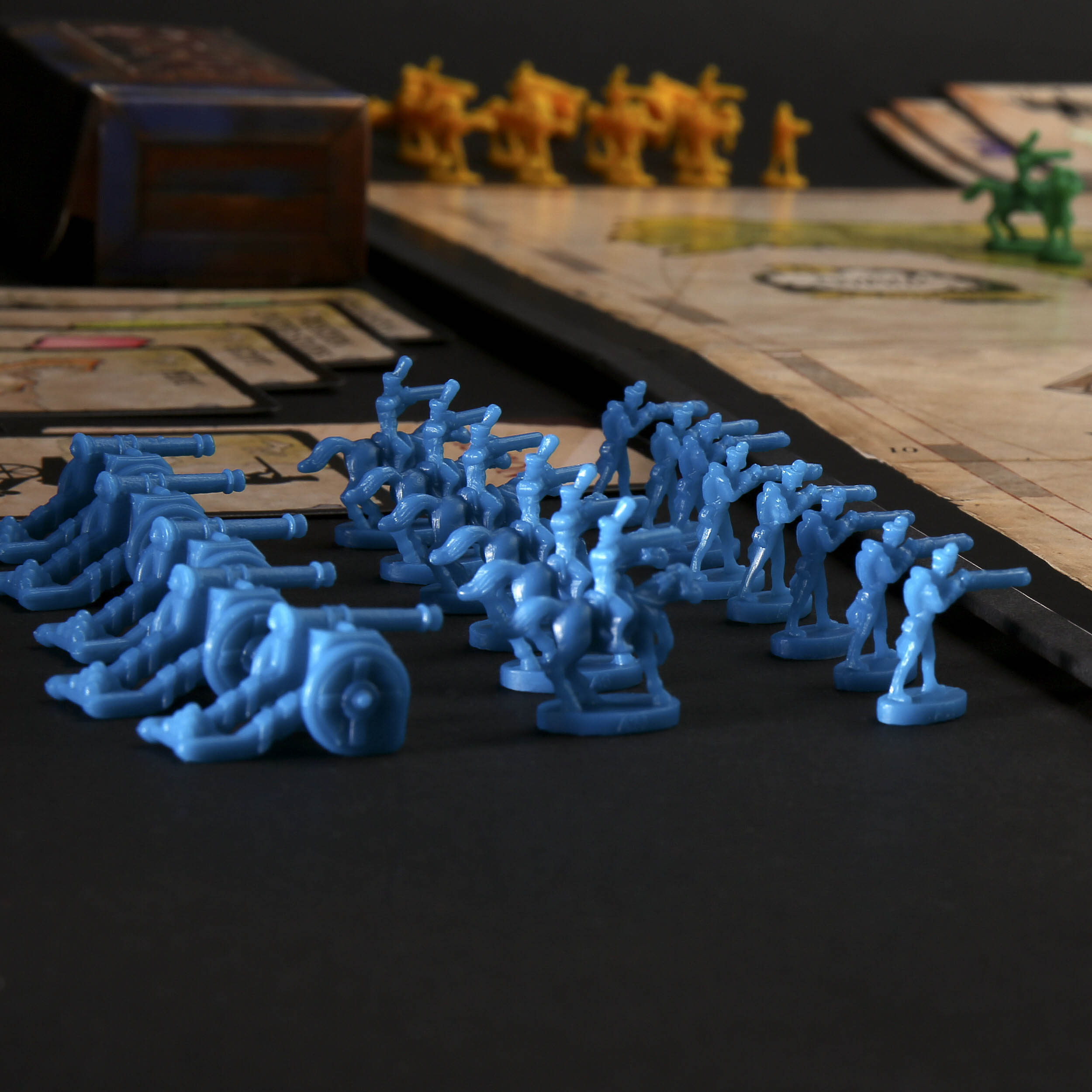 Ein Brettspiel-Szene mit blauen Plastik-Soldatenfiguren und Spielsteinen auf schwarzem Untergrund.