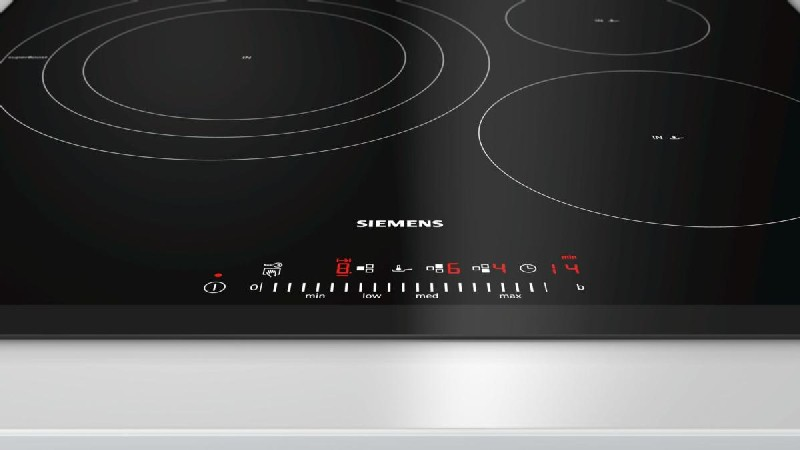 Primer plano de una placa de inducción negra con pantalla digital y botones de control.