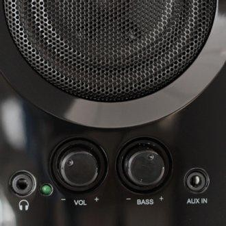 Primer plano de un altavoz negro con controles de volumen, graves y aux. El altavoz tiene una cubierta de malla metálica.