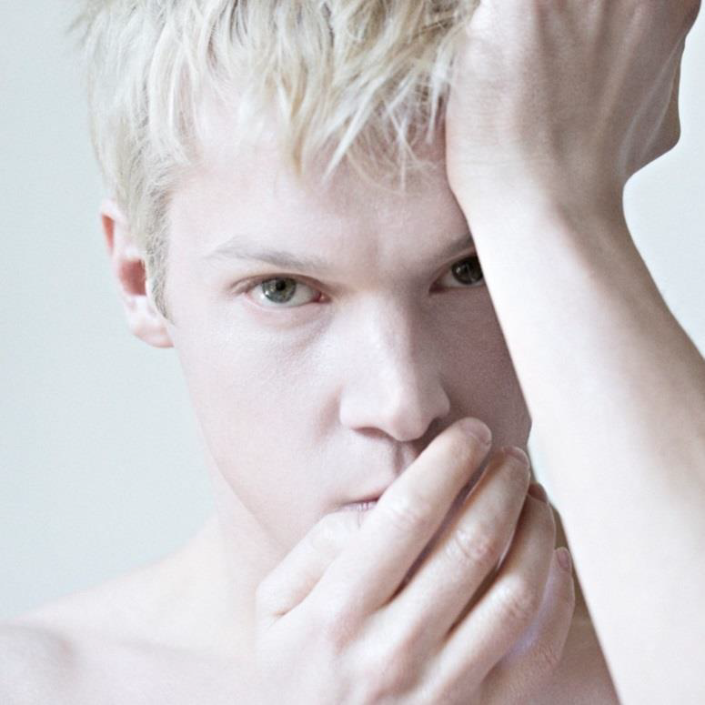 Personne blonde avec la main sur la tête, couvrant la bouche.