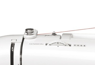 Primer plano de una máquina de coser con un dial de tensión y un hilo rojo que pasa.