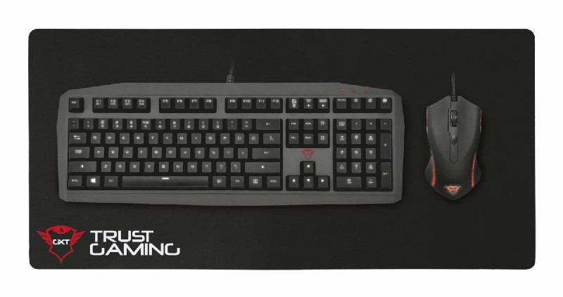 Teclado, ratón y alfombrilla negros. La alfombrilla dice TRUST GAMING.