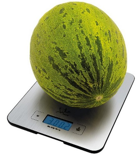 Un melón verde y amarillo en una balanza digital. La balanza marca 3.002.