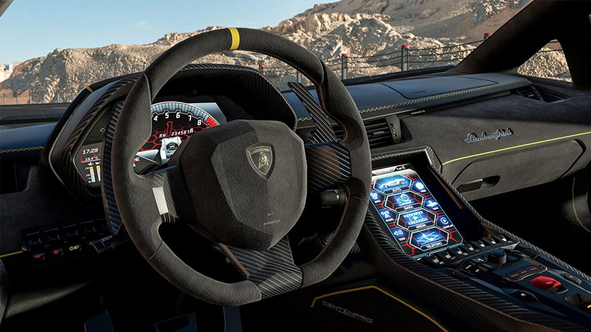 Interior de un Lamborghini, mostrando el volante, el salpicadero con pantalla y vista de la montaña por el parabrisas.