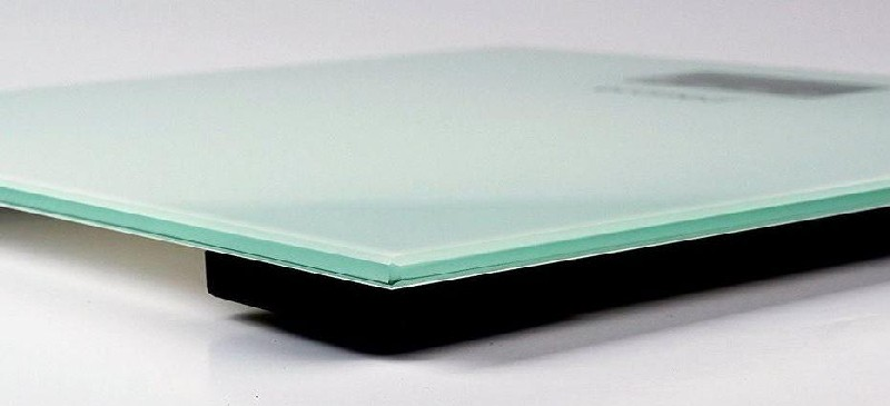 Primer plano de una báscula digital. Una base negra soporta una superficie de vidrio transparente.