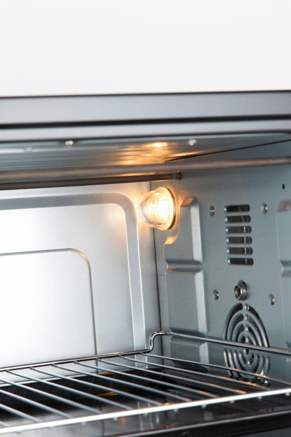 Interior de un horno, iluminado por una luz. Una rejilla de metal es visible.