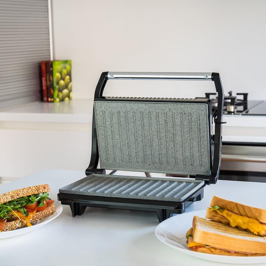 Sandwichera con sándwiches. Dos sándwiches están colocados en platos. Mesa blanca.