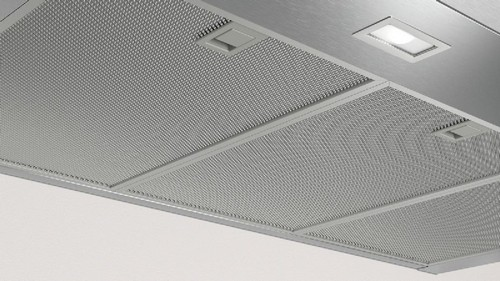 Vista inferior de una campana extractora de acero inoxidable. Tiene un filtro de malla y una luz.