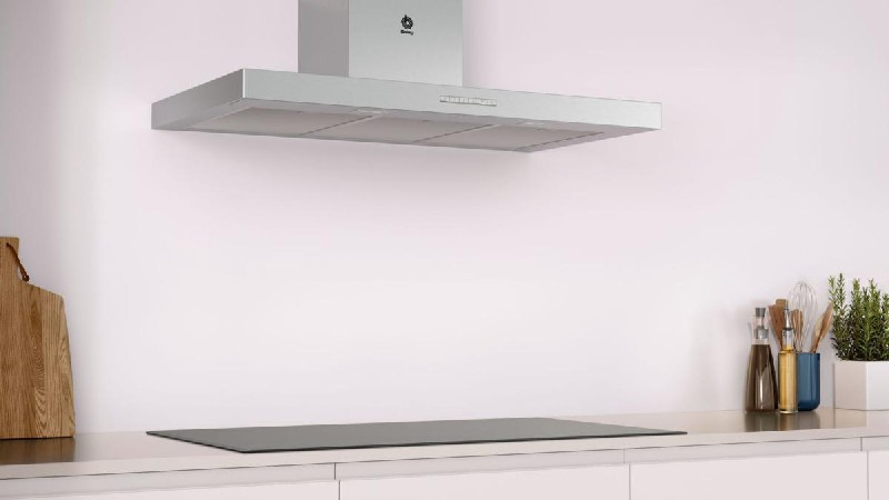Campana extractora y placa de inducción. Paredes blancas y encimera; diseño minimalista.