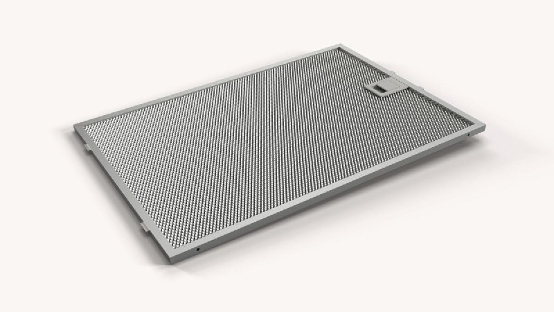 Un filtro de campana rectangular metálico con diseño de malla, en ángulo sobre una superficie blanca.