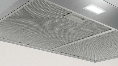 Primer plano de un filtro de aire de malla con una luz arriba. Tonos metálicos y blancos.