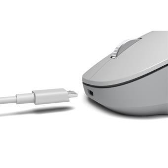 Un ratón de computadora blanco con un cable de carga enchufado. El ratón es gris.