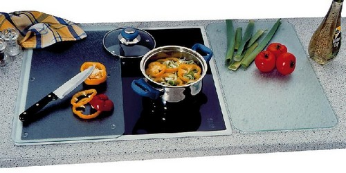 Encimera de cocina con tablas de cortar, verduras y olla en la estufa.