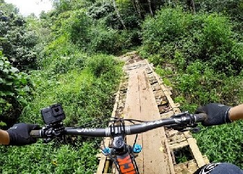 Vista de un ciclista de montaña. El ciclista cruza un puente de madera en un bosque.