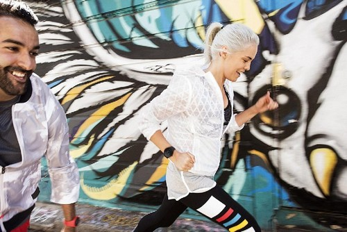 Dos personas corriendo frente a una pared de graffiti colorida. Un hombre y una mujer corren.
