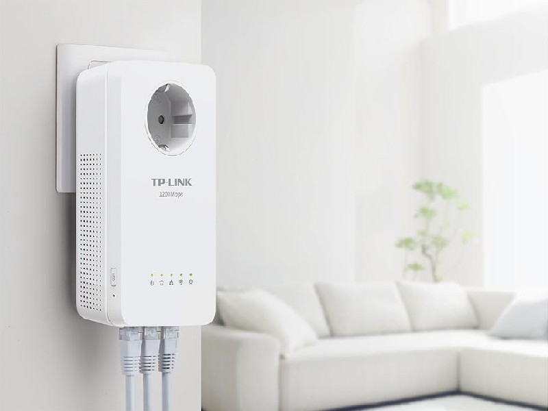 Un adaptador TP-Link Powerline blanco enchufado a una toma de corriente, con cables Ethernet.
