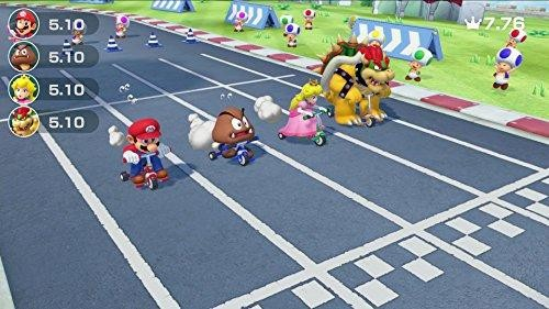 Escena de Mario Kart: Mario, Peach, Bowser y Goomba compiten en karts. Una multitud observa en una pista.