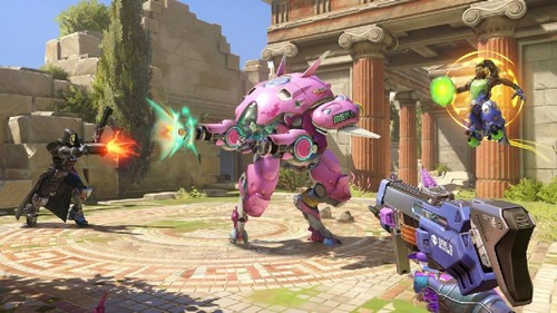 Escena del juego Overwatch con personajes en acción, un robot y una persona disparando ráfagas de energía.
