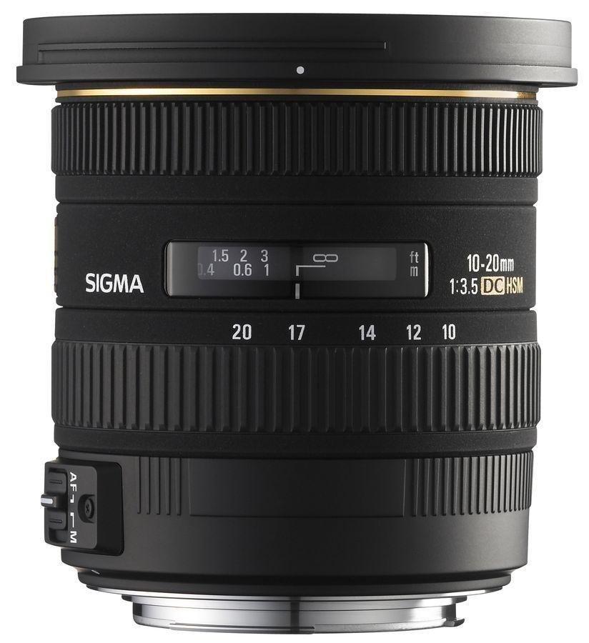 Lente Sigma. Negro con marcas doradas. Tiene números y ajustes para enfoque y apertura.