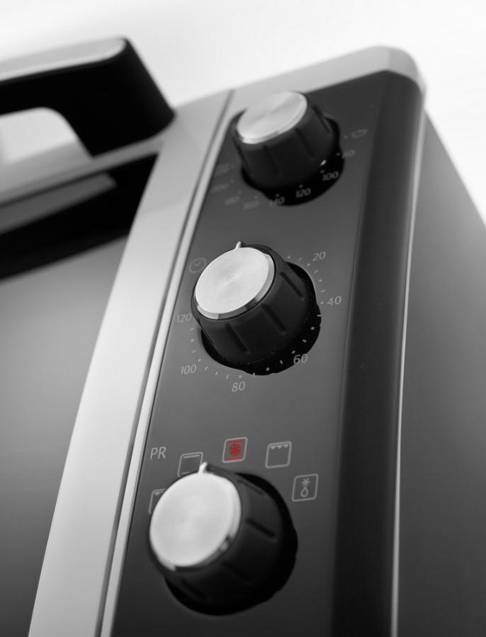 Primer plano de las perillas de control de un electrodoméstico oscuro.