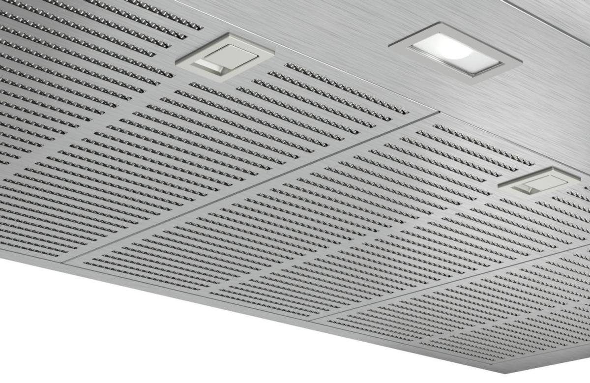 Panel de techo plateado perforado con luces empotradas y pequeñas trampillas cuadradas.