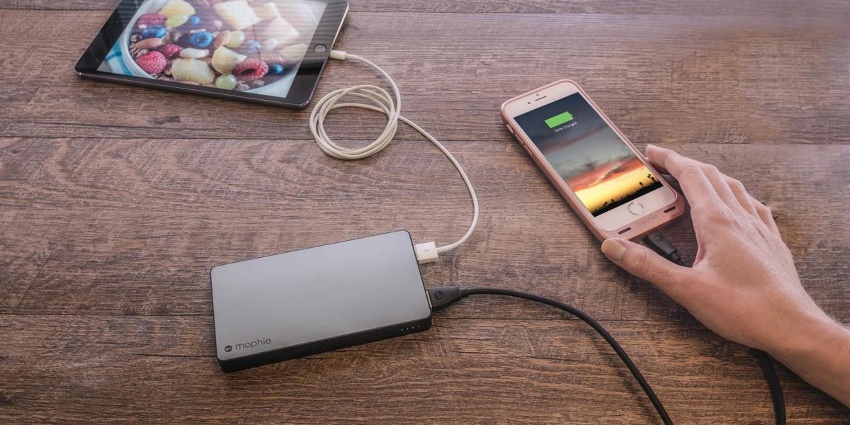 Un cargador móvil conectado a una tableta y un teléfono. Teléfono mostrando el estado de carga.