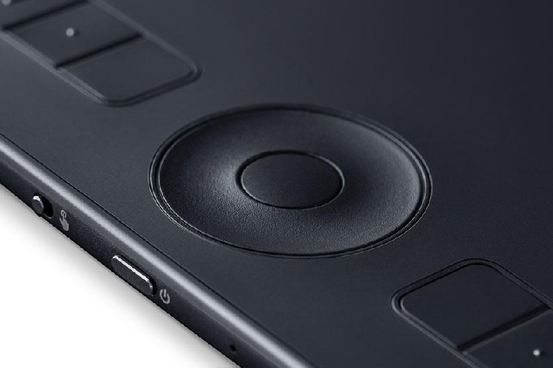 Primer plano de una tableta gráfica negra con sensor táctil circular y botones.