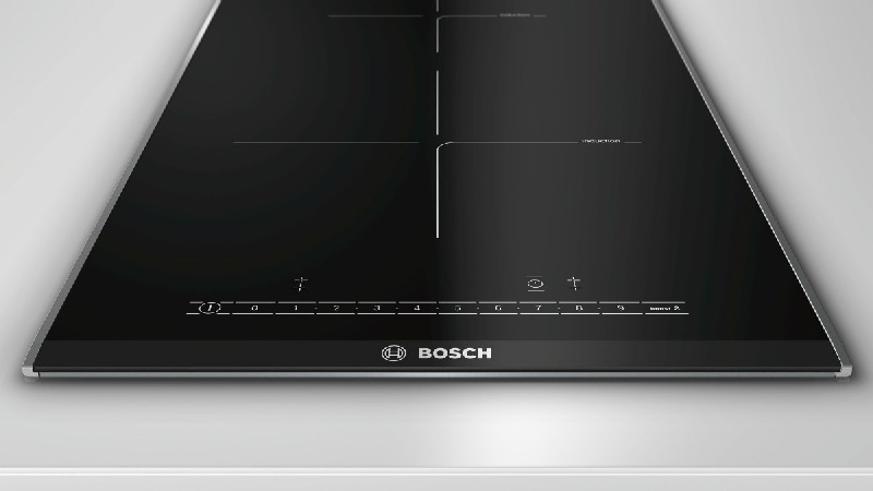Encimera de inducción negra con cuatro zonas de cocción, controles táctiles, marca BOSCH.